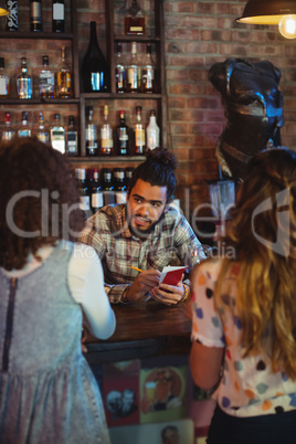 Bartender taking an order on notepad at counter