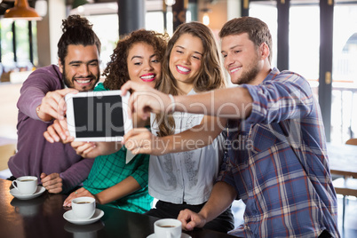 Friends taking selfie with digital tablet in restaurant