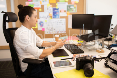 Designer using phone at creative office desk