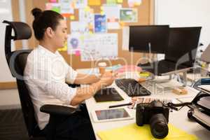 Designer using phone at creative office desk