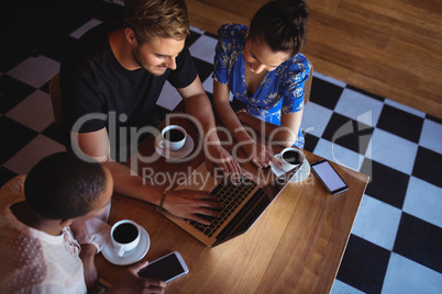 Friends using laptop while having coffee