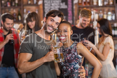 Portrait of young couple embracing while holding beer mugs