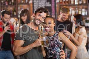 Portrait of young couple embracing while holding beer mugs