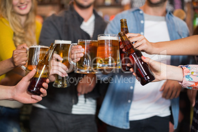 Friends toasting beer glasses and bottles in pub