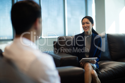 Businesswoman holding digital tablet while discussing with male colleague