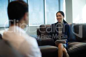 Businesswoman holding digital tablet while discussing with male colleague