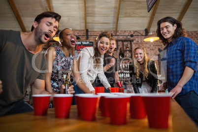 Young friends playing beer pong game in bar