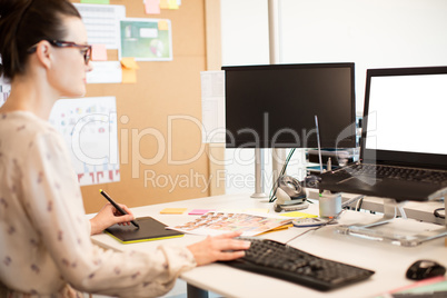 Young businesswoman working on digitizer while using keyboard