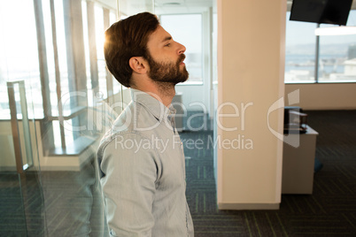 Side view of sad businessman leaning on glass