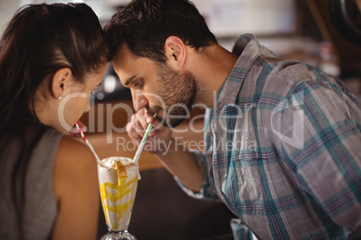 Close-up of couple having milkshake