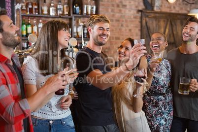 Friends laughing together while holding drinks