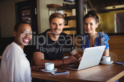 Portrait of friends using laptop while having coffee