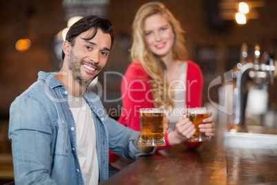 Young man and woman holding beer glasses at pub