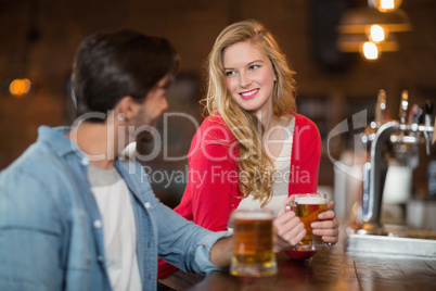 Man and woman looking at each other with holding beer glasses