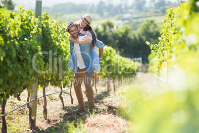 Cheerful couple taking selfie while piggybacking at vineyard