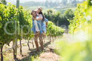 Cheerful couple taking selfie while piggybacking at vineyard