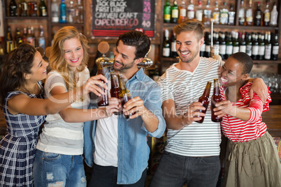Group of friends toasting beer bottles at pub