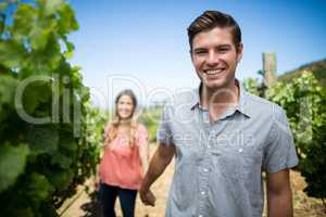 Happy young man holding woman hand at vineyard