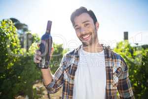 Portrait of man holding wine bottle at vineyard