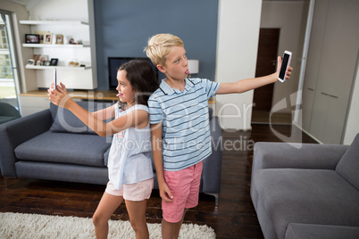 Siblings taking selfie on their mobile phone in living room