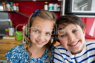 Siblings smiling at camera in kitchen