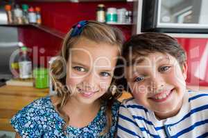Siblings smiling at camera in kitchen