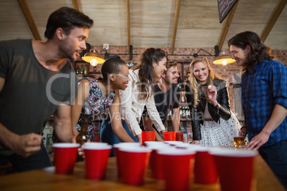 Happy friends playing beer pong game in bar