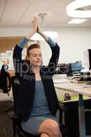 Businesswoman practicing yoga while sitting on chair