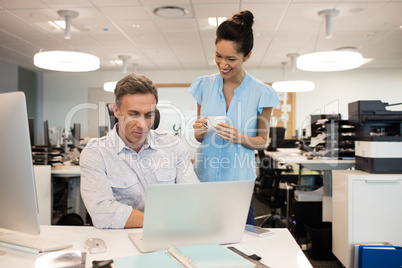 Smiling businesswoman talking with male colleague in office