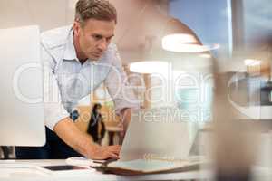 Businessman working on laptop while leaning at desk
