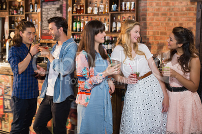 Smiling friends talking while holding drinks