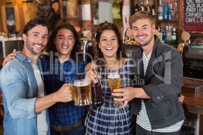 Portrait of friends tossing beer glasses and bottles in pub