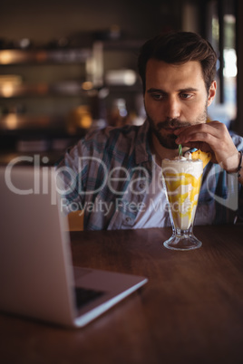 Man using laptop while having milkshake