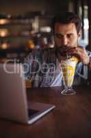 Man using laptop while having milkshake