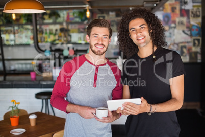 Portrait of smiling young friends using digital tablet in restaurant
