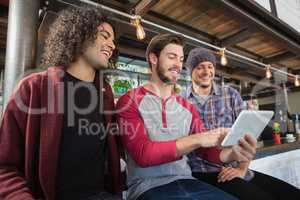 Happy male friends using digital tablet in restaurant