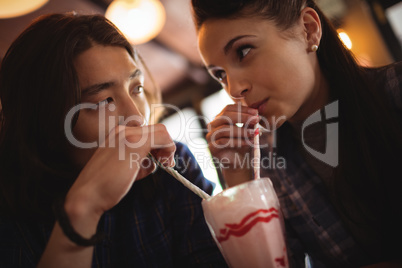Close-up of couple having milkshake