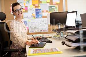 Portrait of smiling businesswoman working on digitizer at office