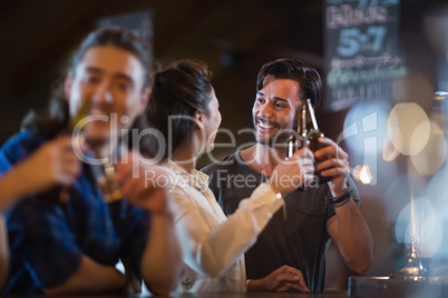 Smiling friends toasting beer bottles