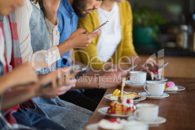 Group of friends using mobile phone while sitting at table