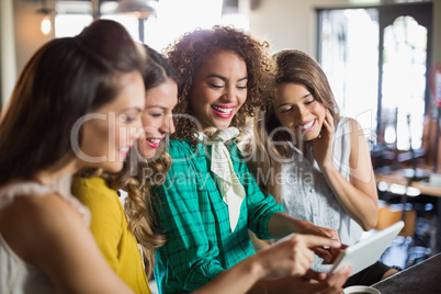 Female friends using digital tablet in cafe