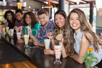 Cheerful friends having smoothie at restaurant