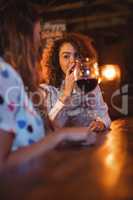Two young women having red wine in pub