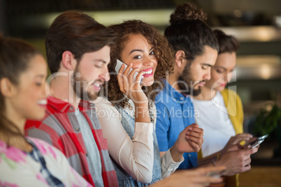 Woman talking on smartphone while friends using mobile phone