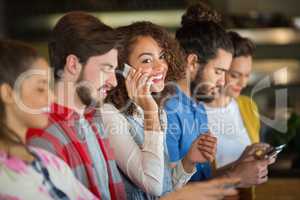 Woman talking on smartphone while friends using mobile phone