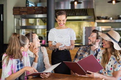 Waitress writing orders of customers in restaurant