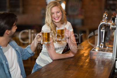 Young woman toasting beer with male friend at pub