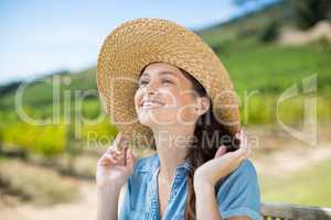 Happy woman wearing sun hat while looking away