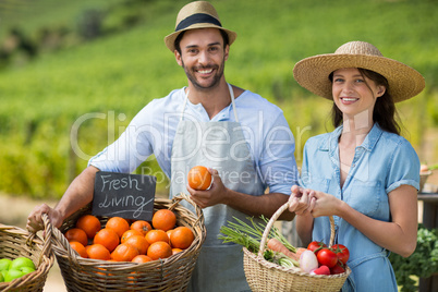 Smiling man and woman standing by fresh vegetables at farmer market