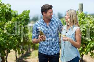 Happy couple looking at each other while holding wine bottle and glass